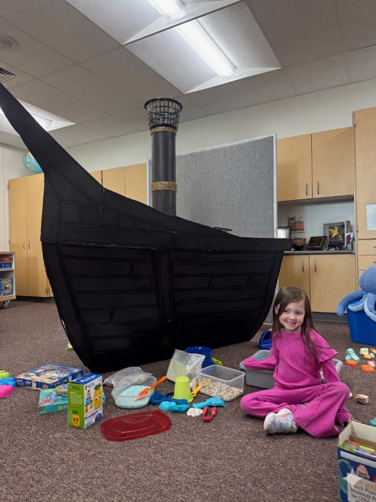 students smiling and fishing in a card board pirate ship
