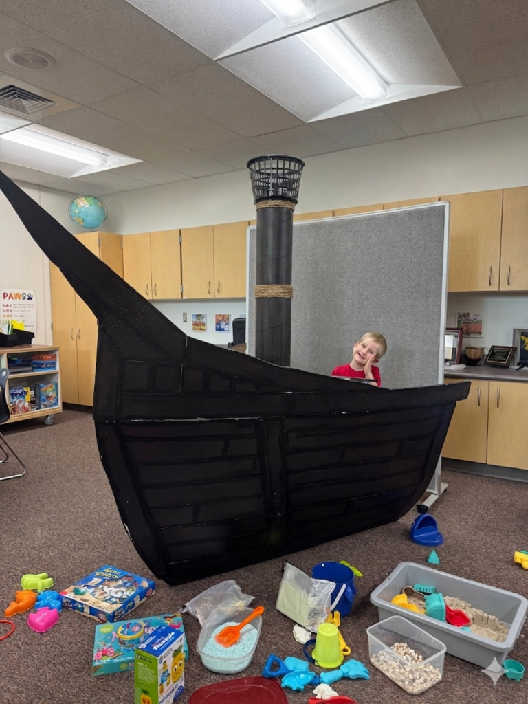 students smiling and fishing in a card board pirate ship