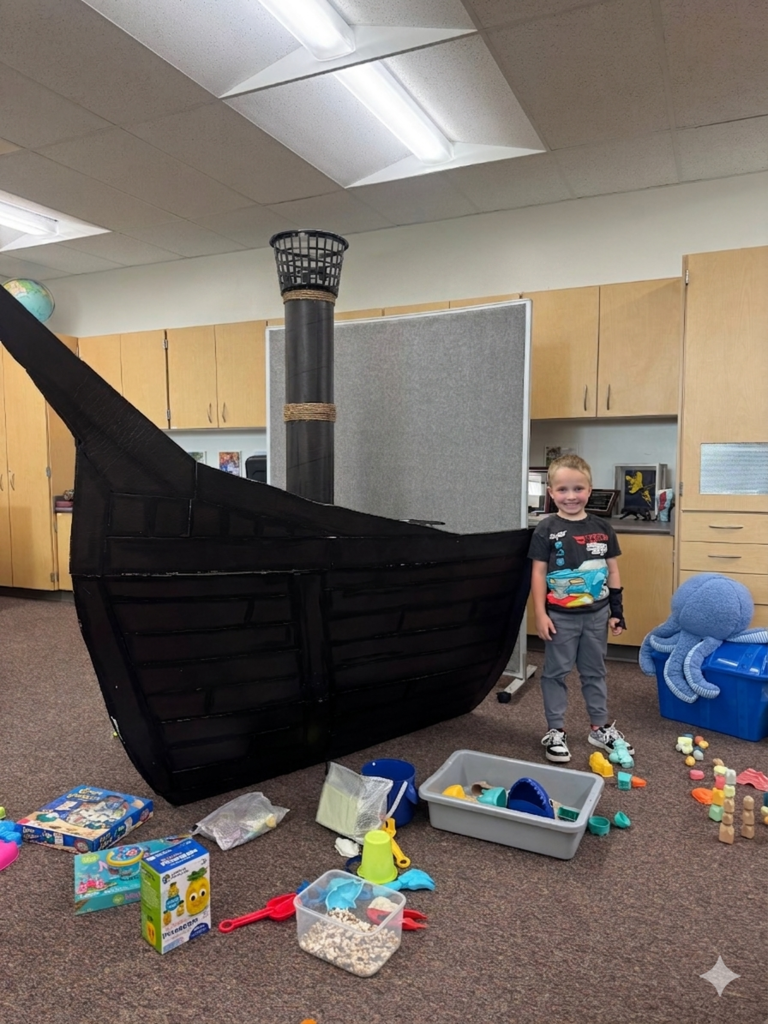 students smiling and fishing in a card board pirate ship
