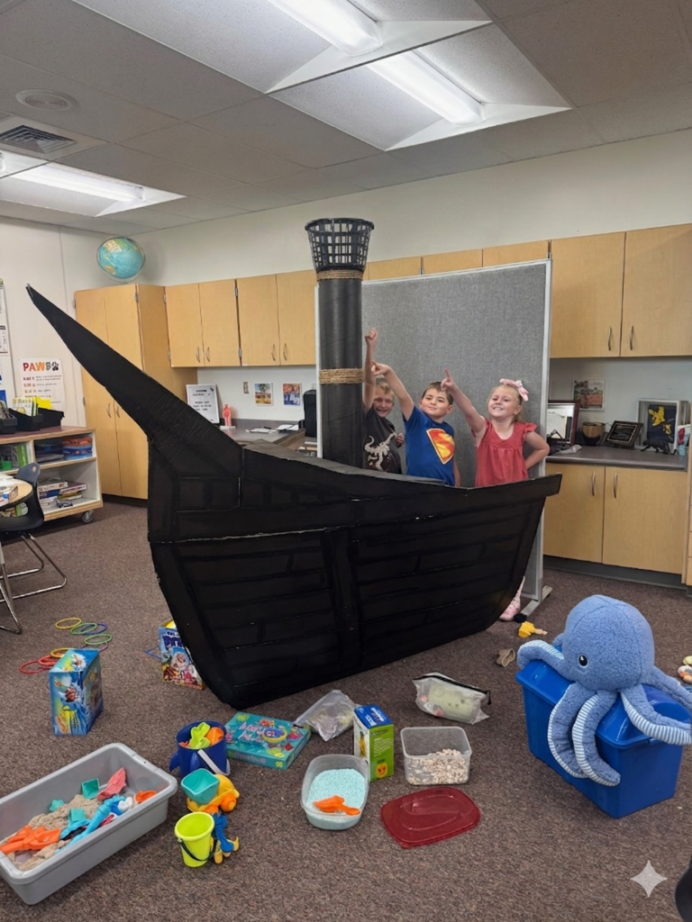 students smiling and fishing in a card board pirate ship