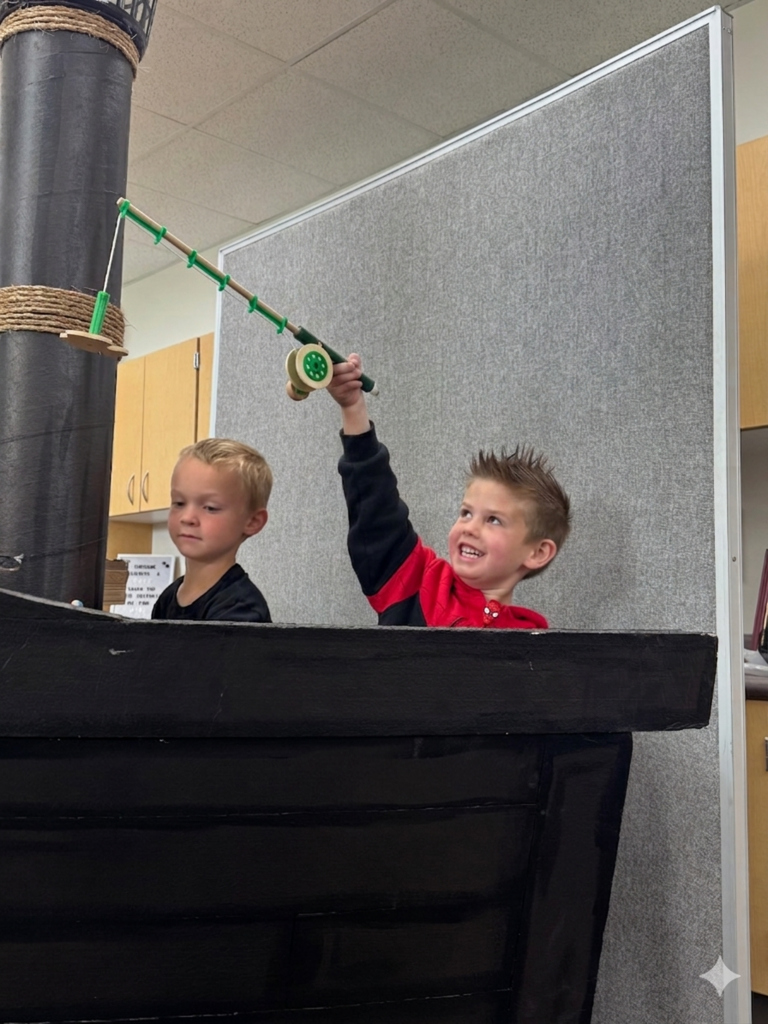 students smiling and fishing in a card board pirate ship