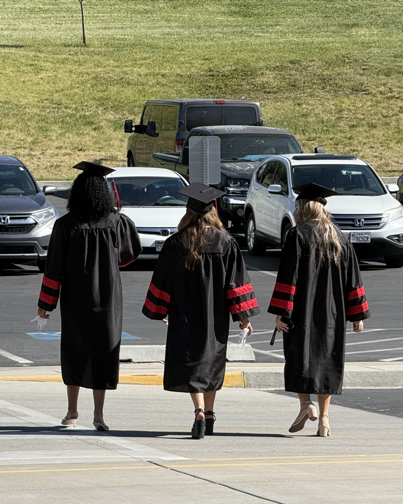 Three graduates walking away from the school. 