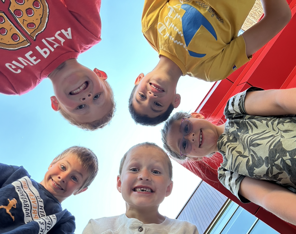 a group of 5 students smiling and looking down at the camera from above