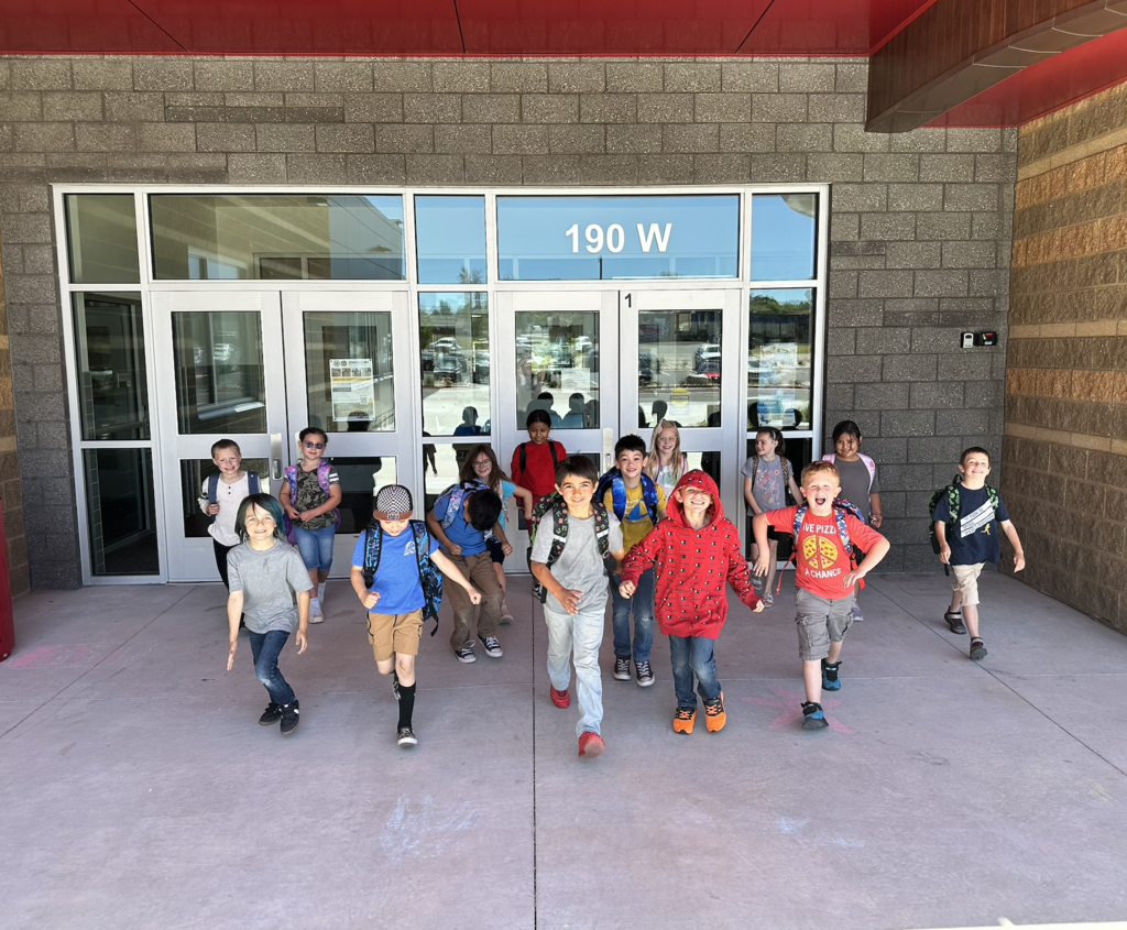 a group of students leaving the school building with happy looks on their faces
