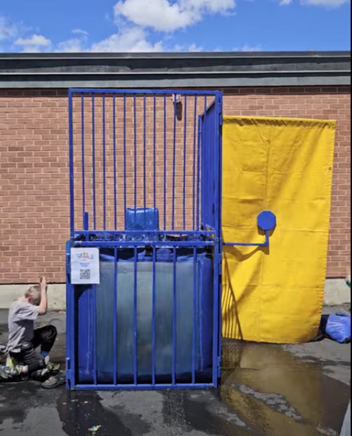 A series of photos showing Dr. Watson, the principal of Lomond View Elementary, participating in a dunk tank event on a sunny day. She is wearing a black shirt and sitting on the collapsible platform above a large blue water tank. One photo captures the moment a student hits the target, and subsequent photos show Dr. Watson submerged in the water and then emerging with a big smile while students cheer her on.