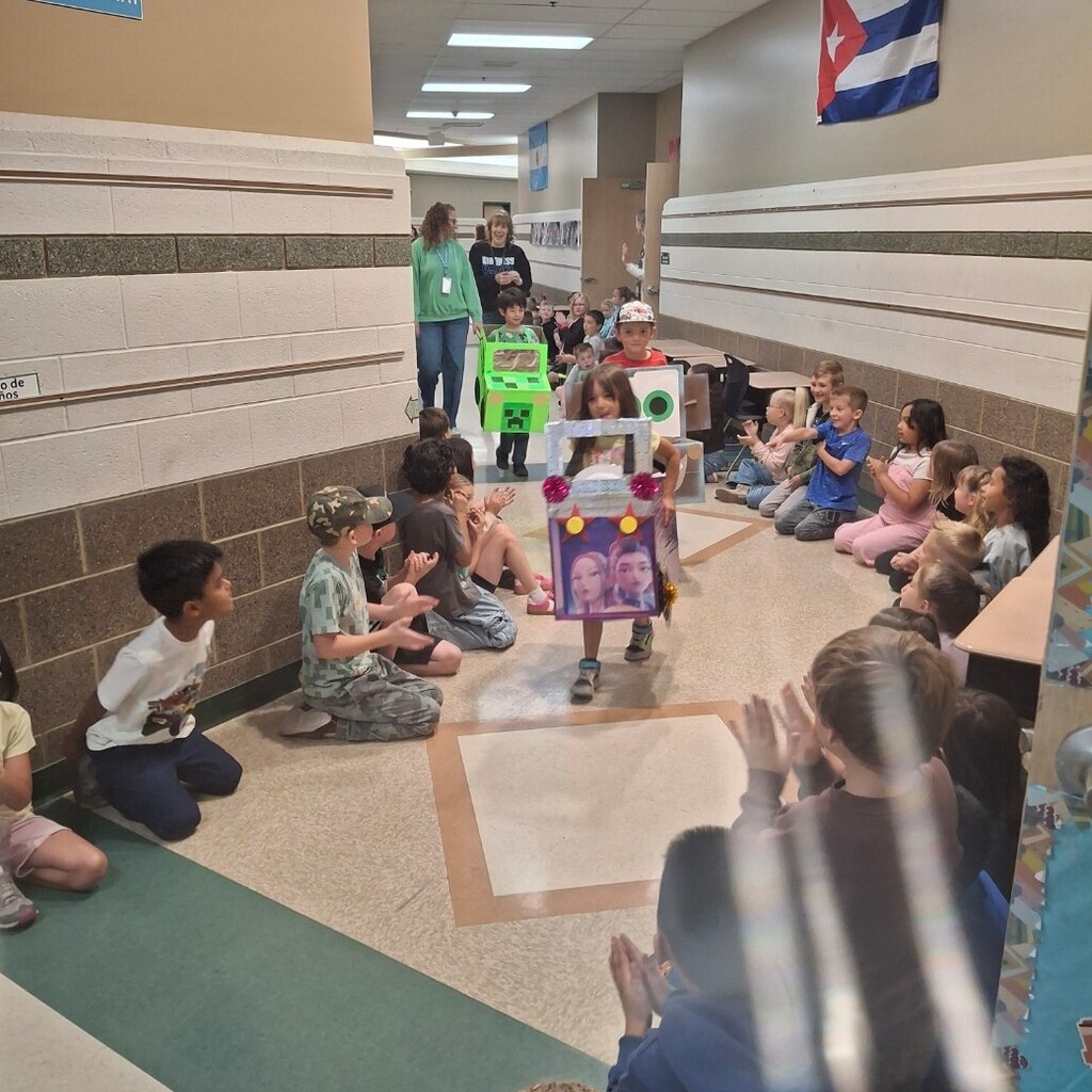 Hallway lined with students watching kindergartners in their cardboard cars.