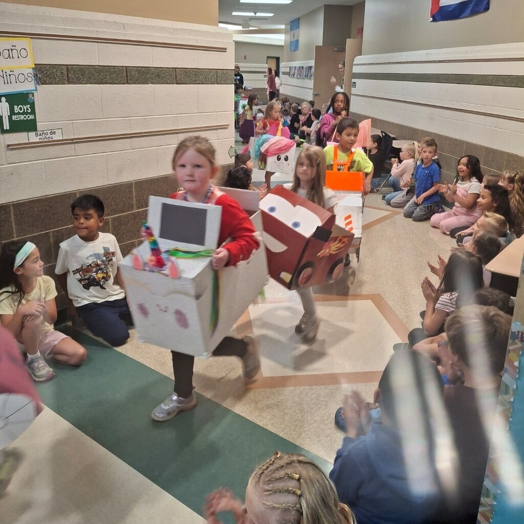 students lined the hall watching kindergarteners in their cardboard cars. 