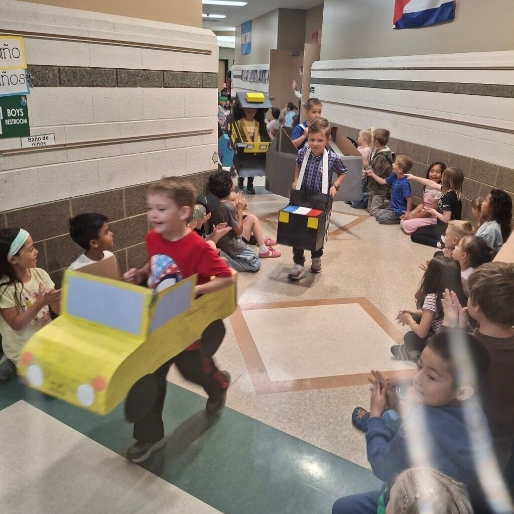 Kids watching kindergartners in their cardboard cars. 
