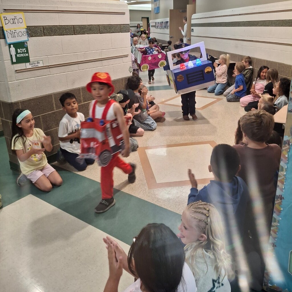 Kids watching kindergartners in their cardboard cars. 
