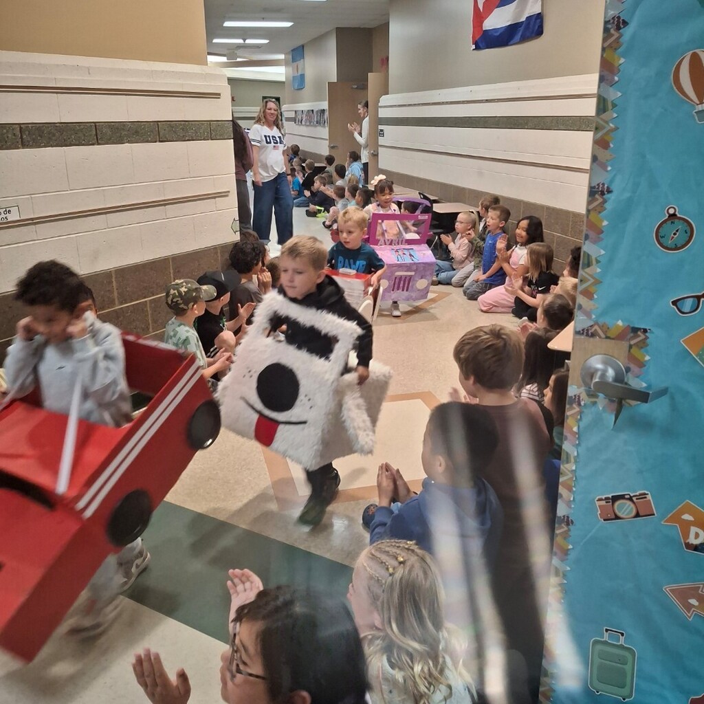 Kids watching kindergartners in their cardboard cars 