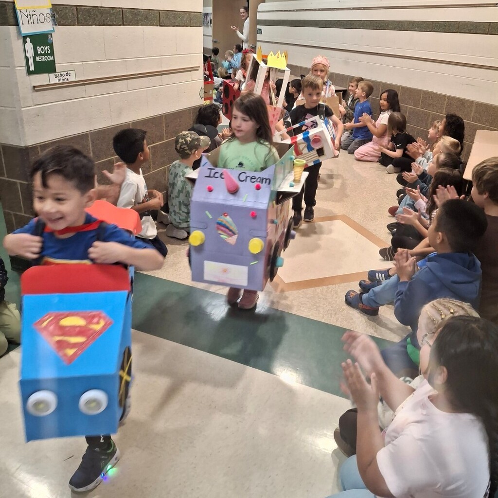 Kids watching kindergartners in their cardboard cars 