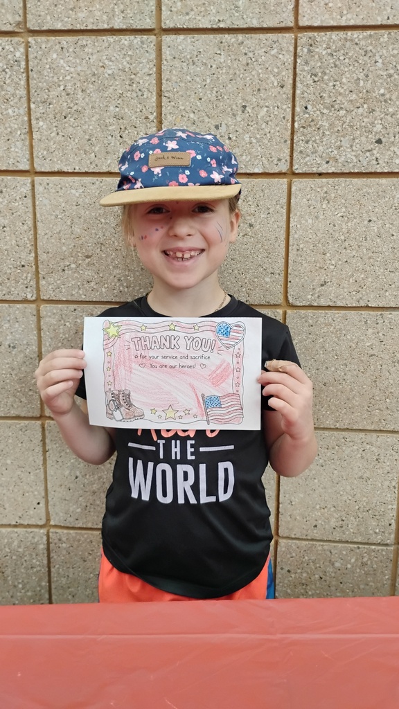 girl smiling with a picture she colored for service members