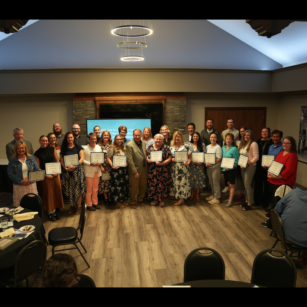 A group of educators holding their awards certificates with district administration at the banquet