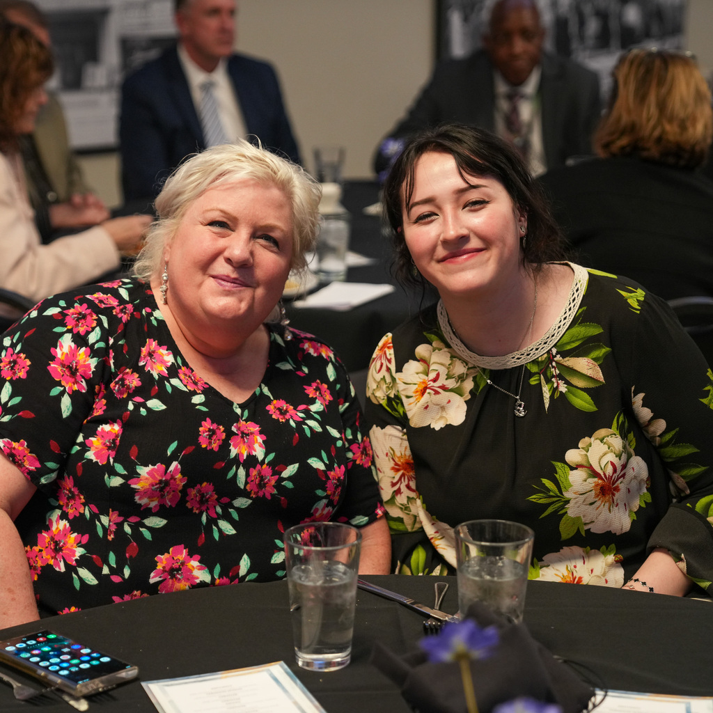 Two female educators smiling sitting at a table.