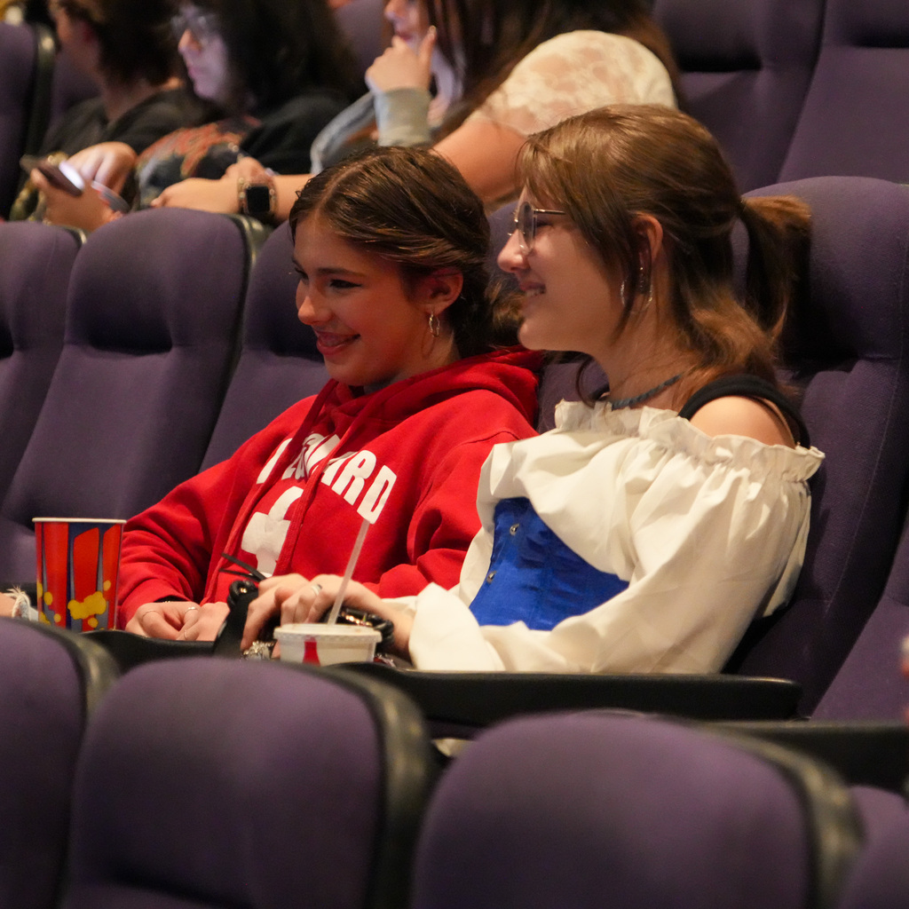 A group of students sitting in the theater smiling towards the camera