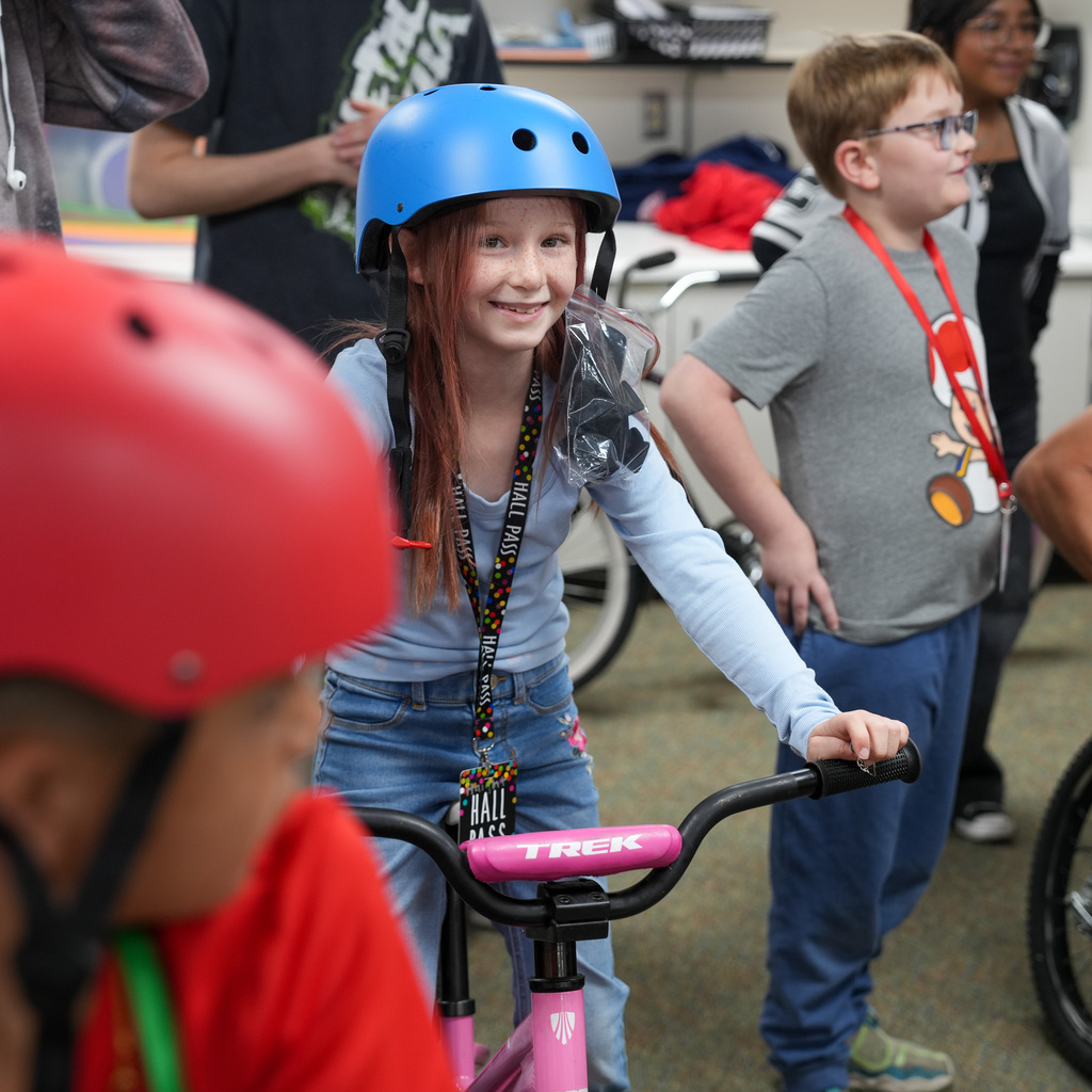 A girl smiles with a helmet on while sitting on the new bike