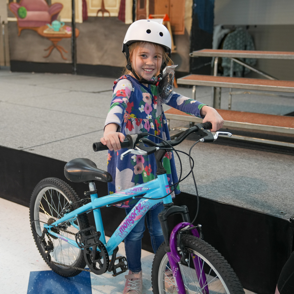 A student with a helmet on smiling next to her bike