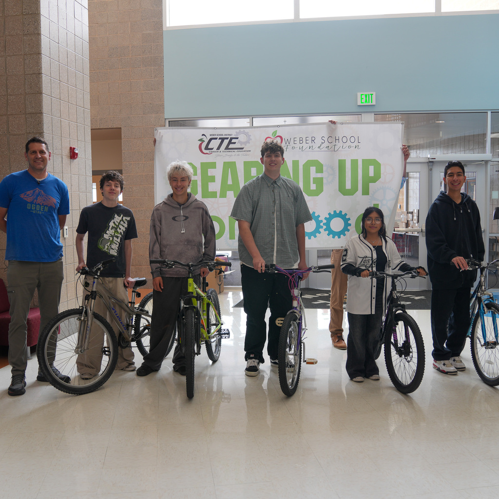 Students standing next to the bikes with a sign held behind them with gearing up for good