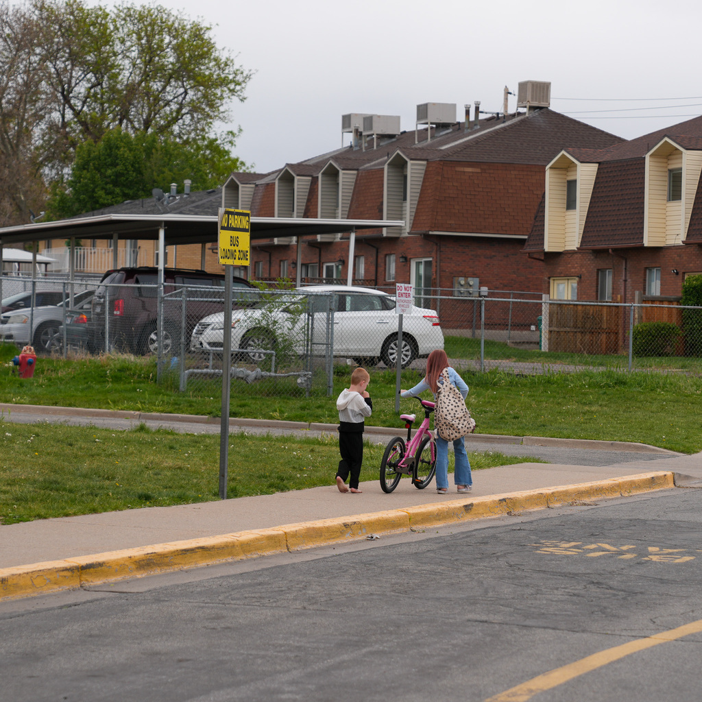 A student walks down the sidewalk with her new bike