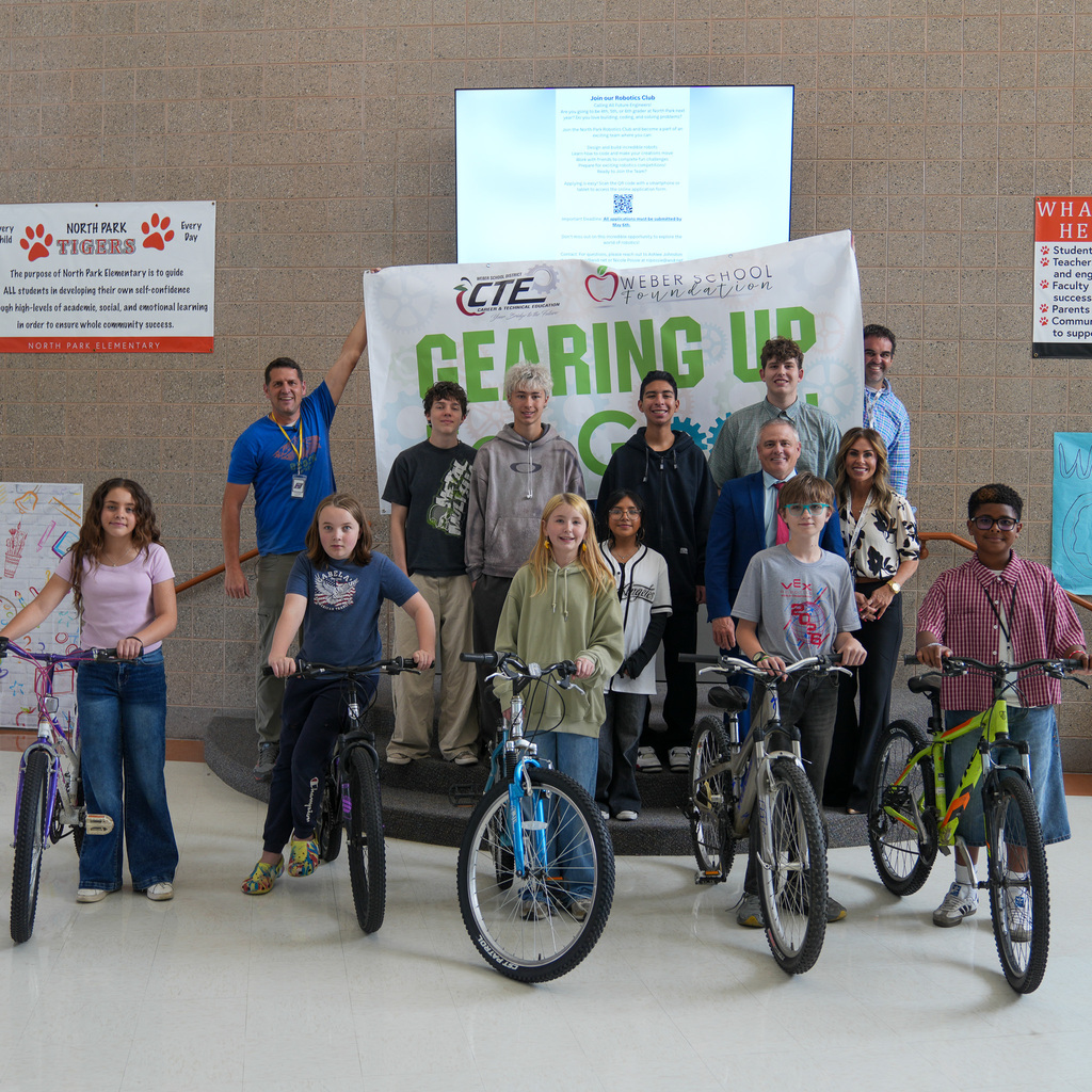 Students standing next to the bikes with a sign held behind them with gearing up for good