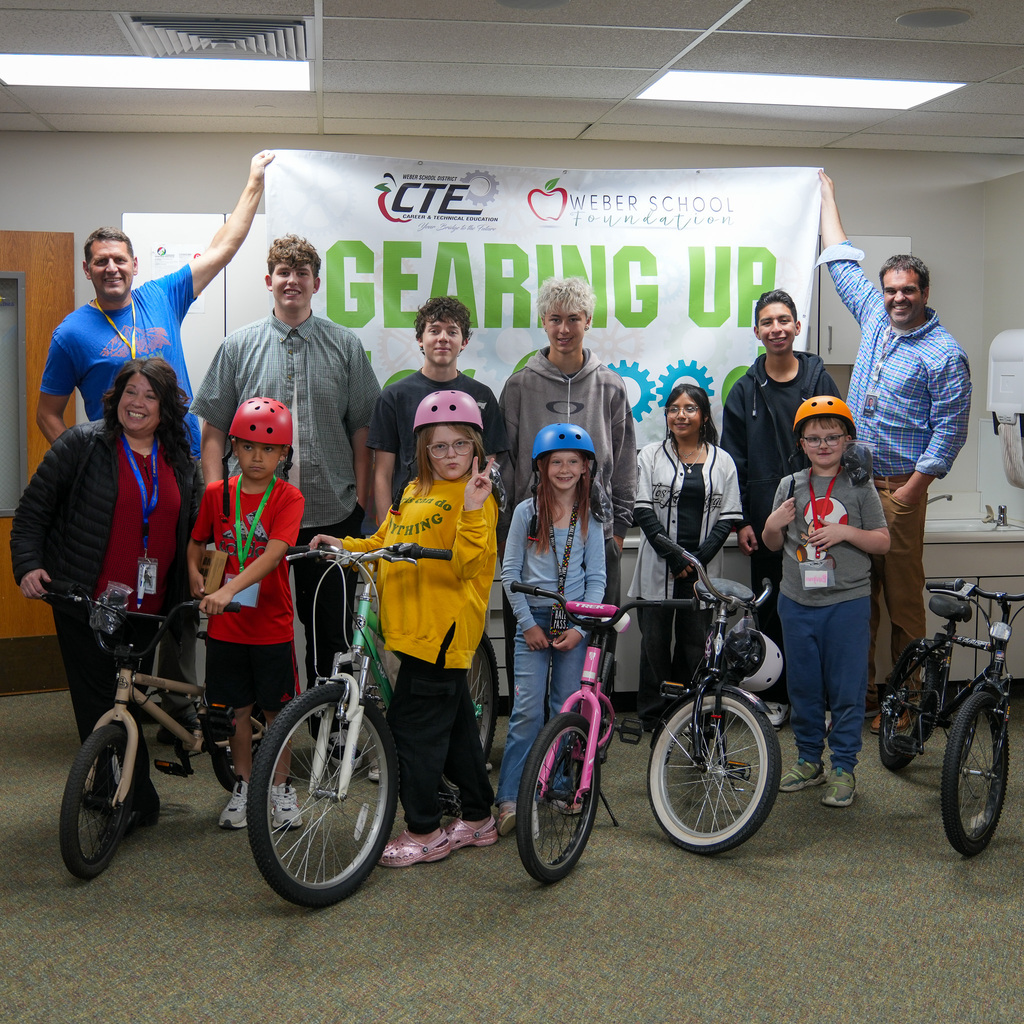 Students standing next to the bikes with a sign held behind them with gearing up for good