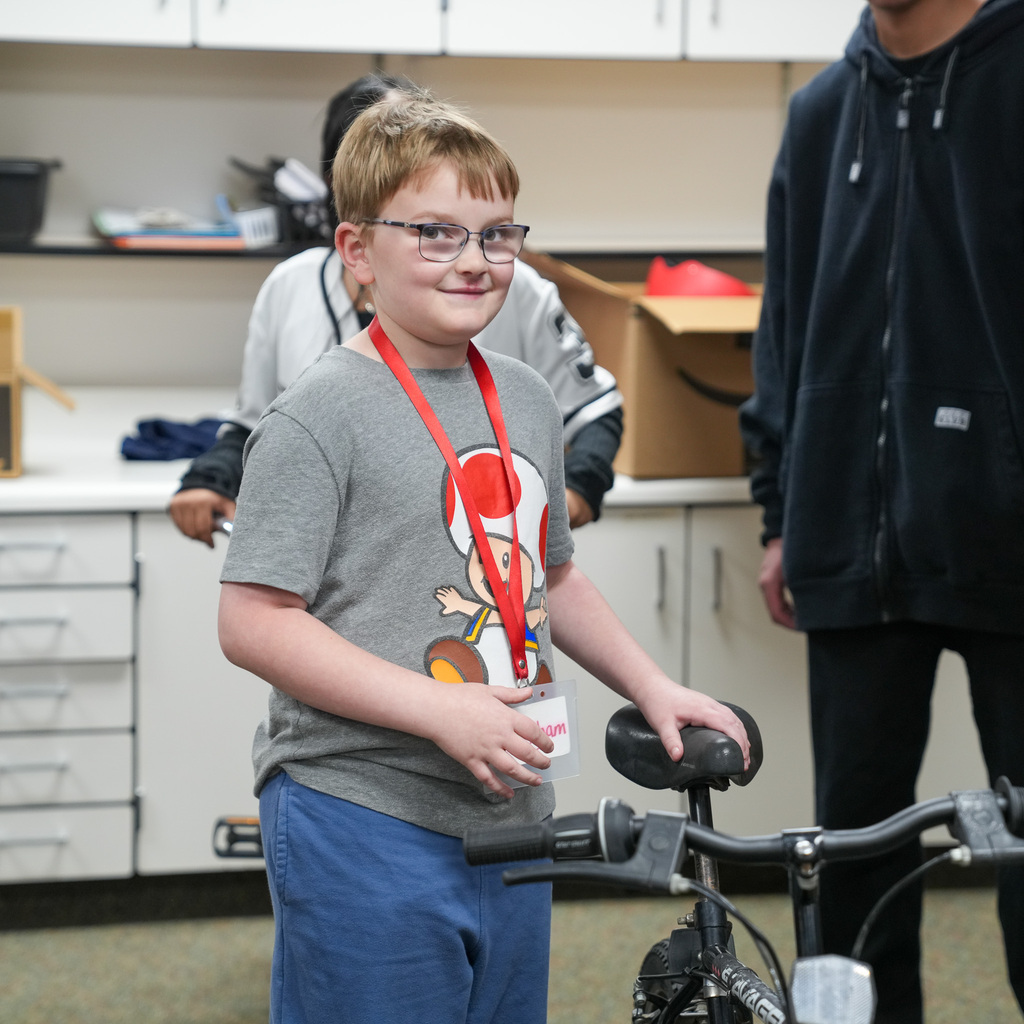 A student proudly stands next to his bike