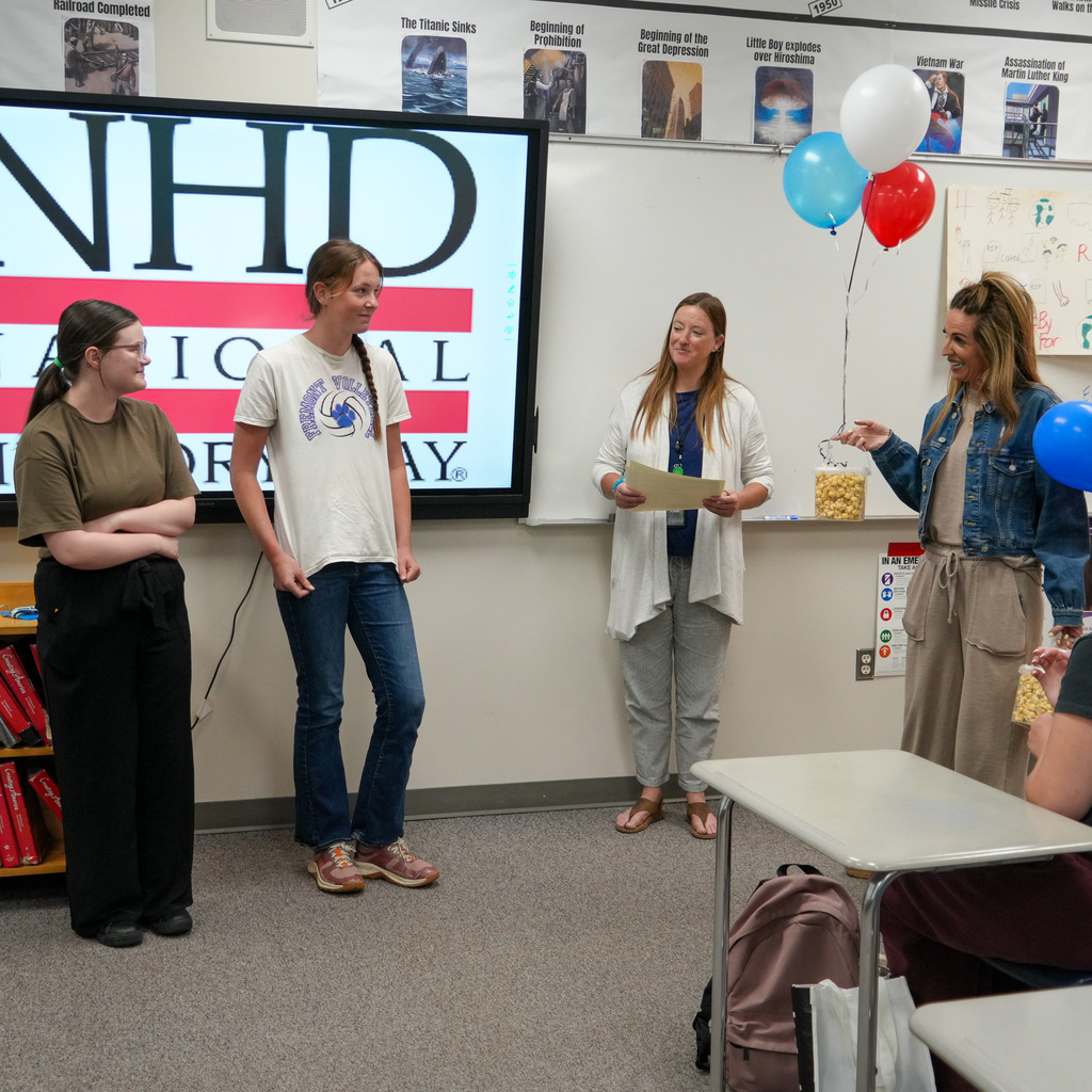 Students being awarded in the front of a classroom