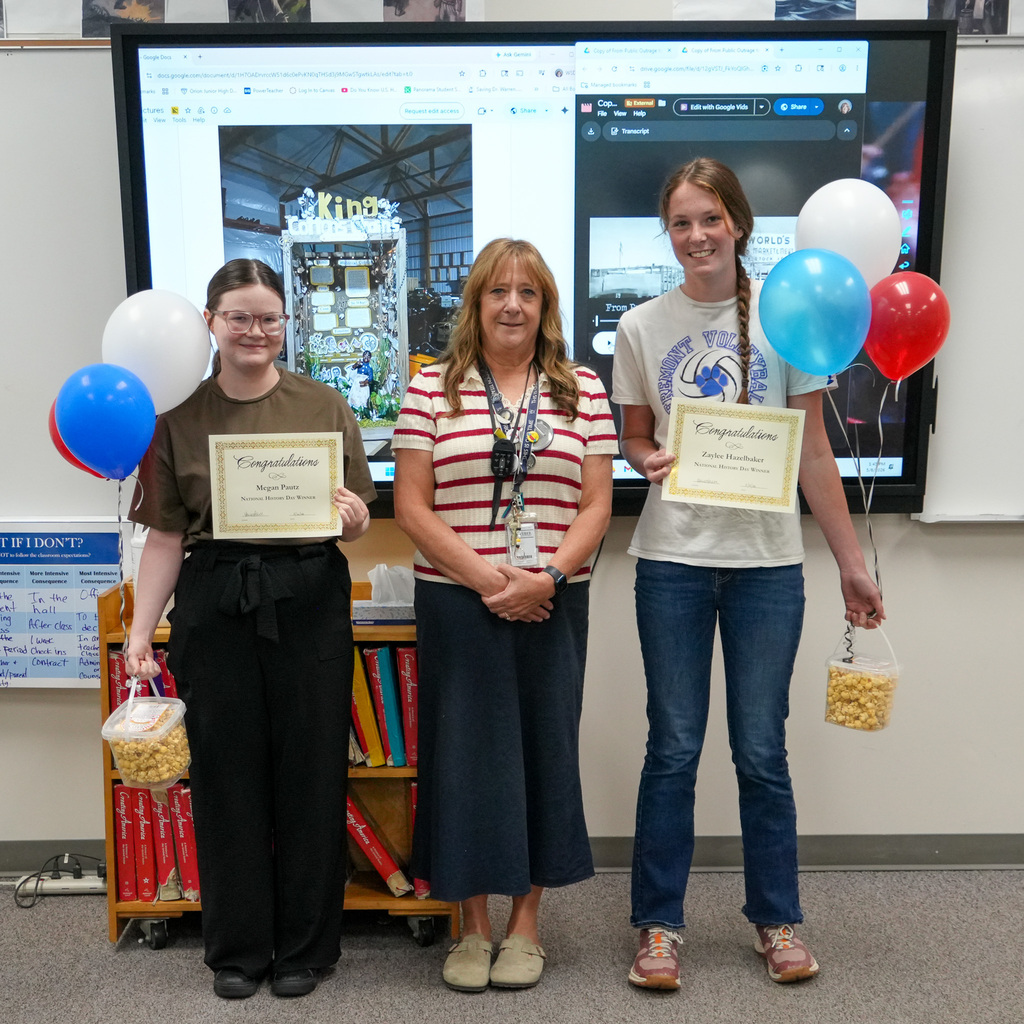 Two students pose with their award certificates along with their teacher