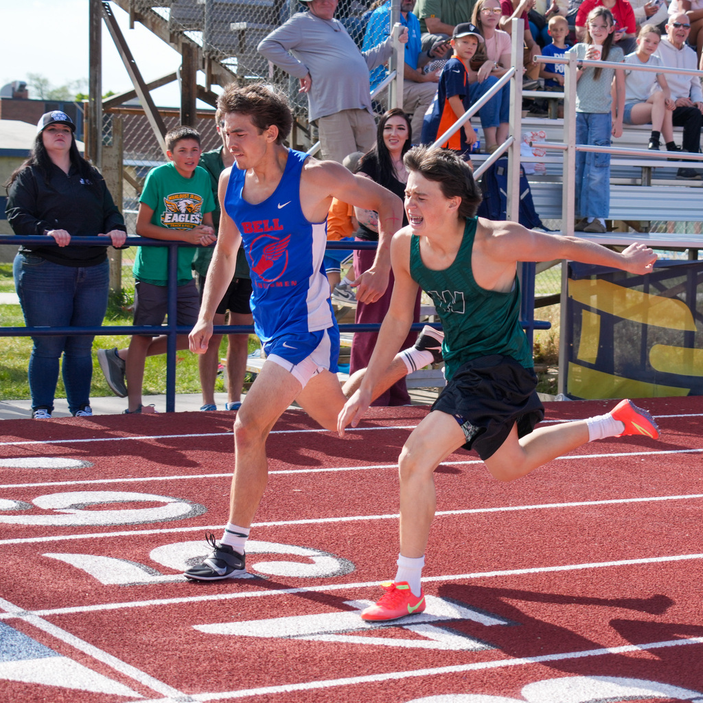 Two boy athletes cross the line neck and neck