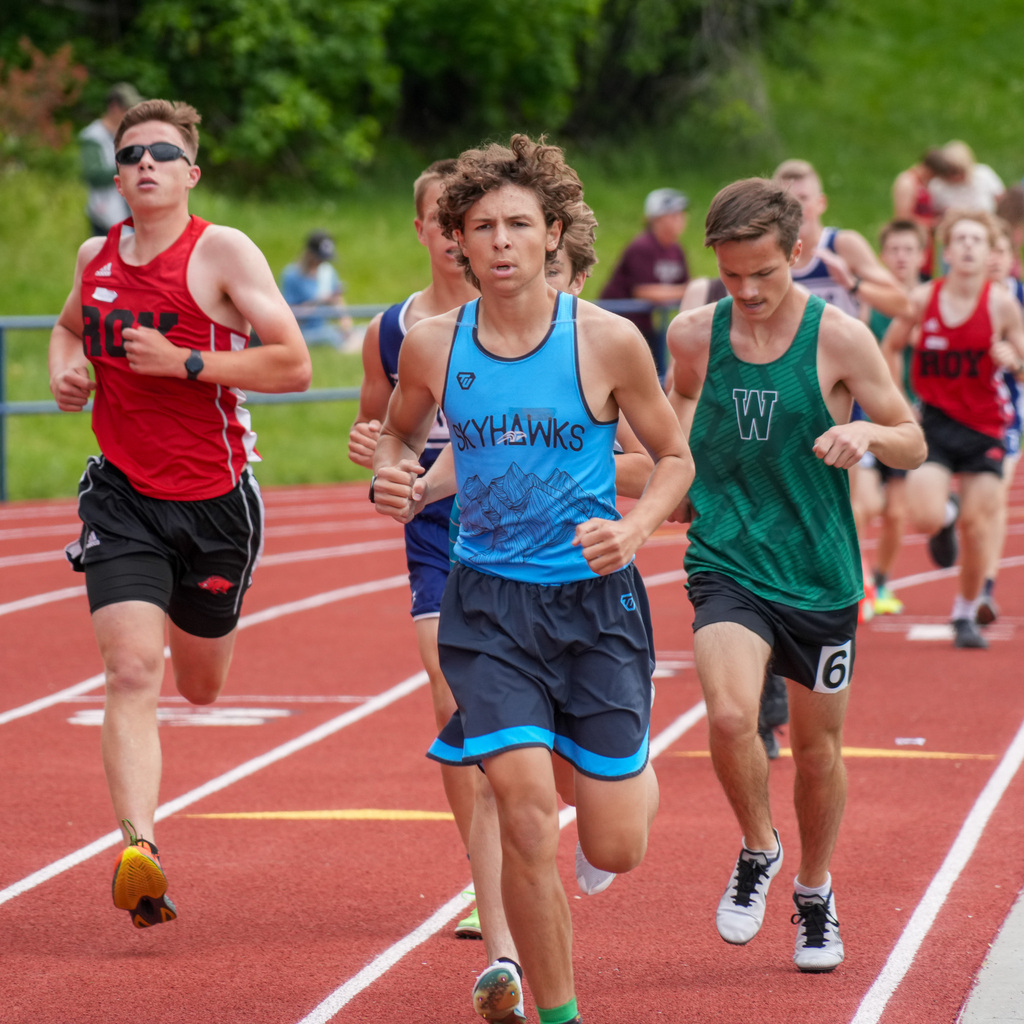 Boy athletes from multiple schools run towards the camera on a track