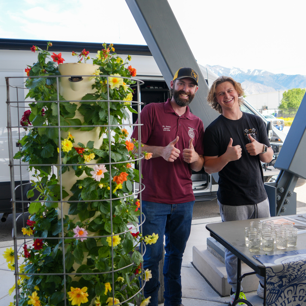 A student and a teacher stand behind a planter tower