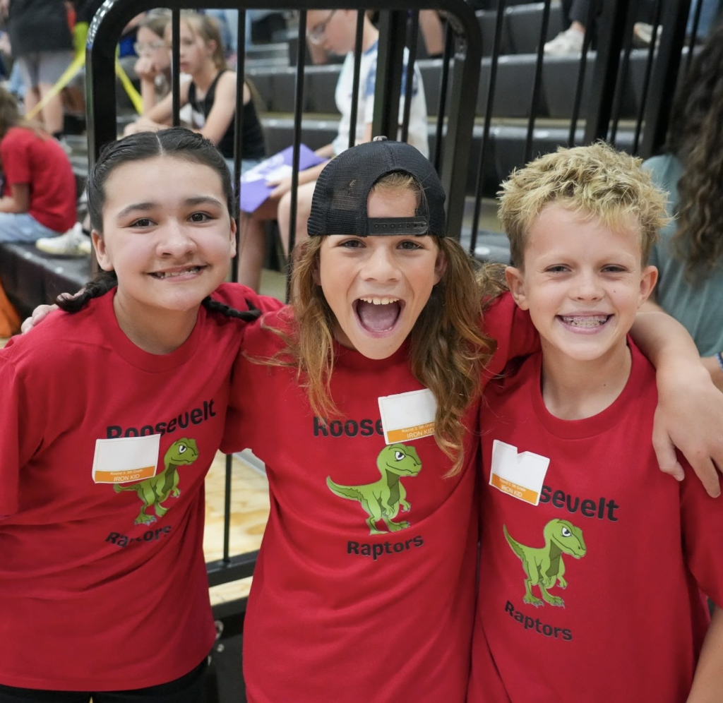 group of 3 students with smiling faces and arms wrapped around each others shoulders