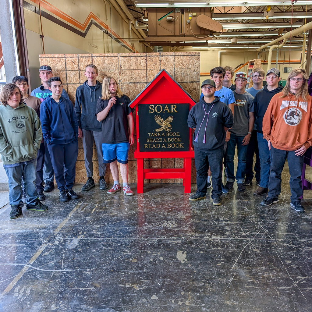 Students are standing next to a completed tiny library