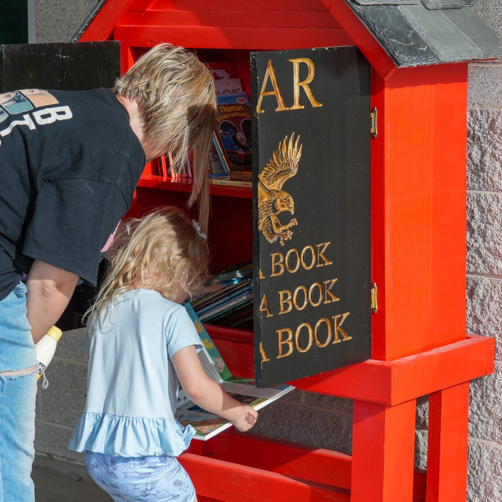 A mother and child look at books in the tiny library outside of a school