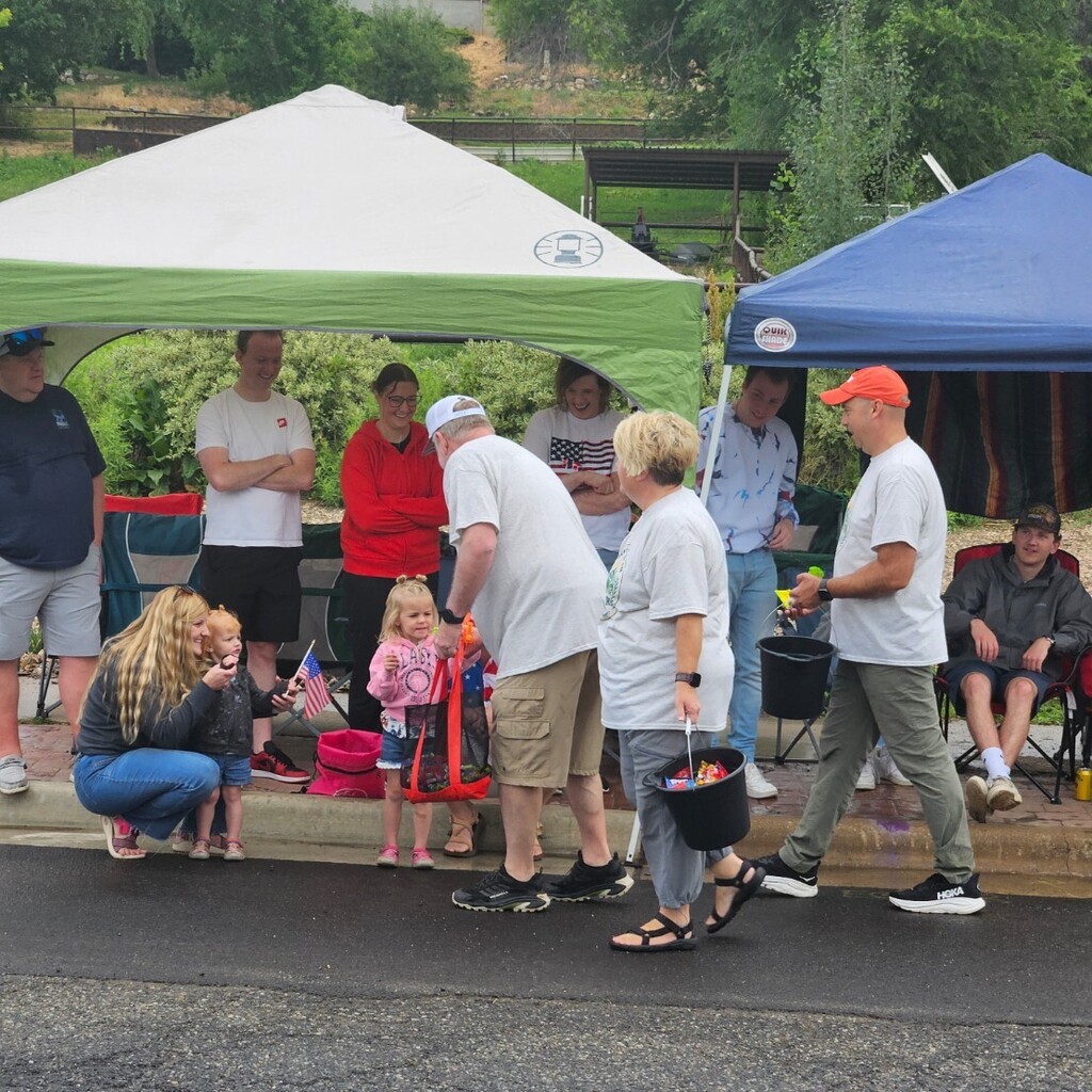 Lomond View Elementary reading aide, Sara Urry, walking alongside the Mayor of Pleasant View, handing out candy from buckets to families and children gathered under pop-up tents along the parade route.
