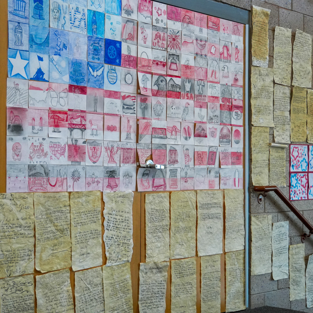 Students artwork form the image of the American flag with writing examples hanging on the wall