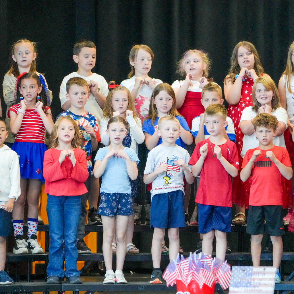 A group of young students standing on a stage singing