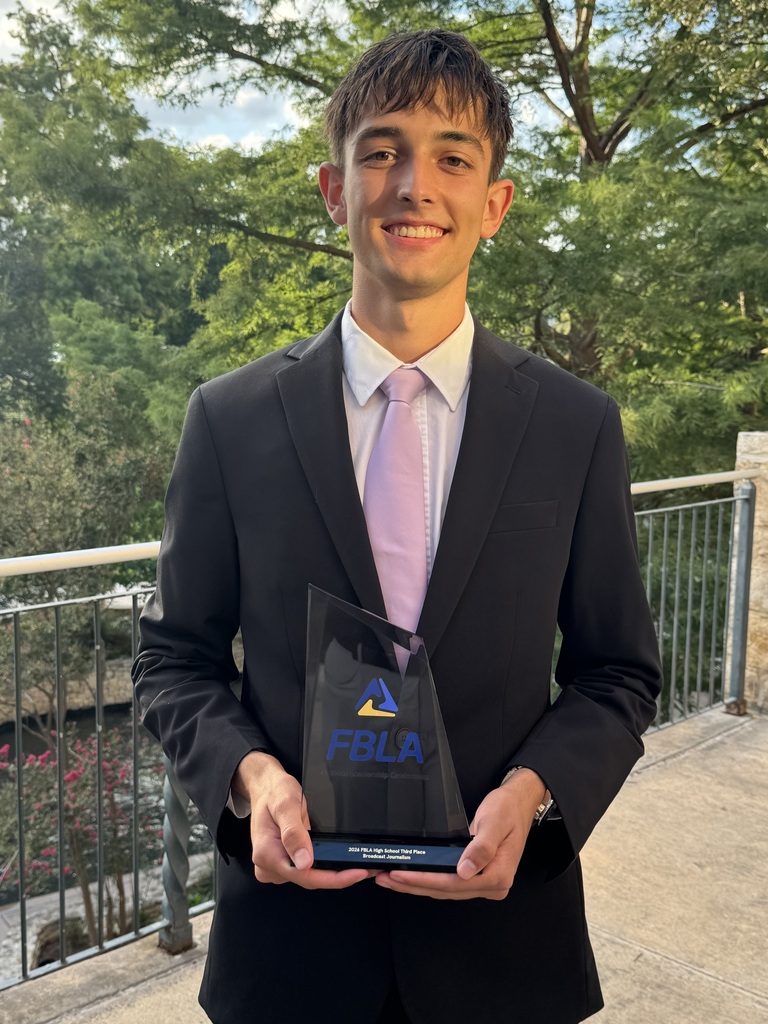 Brady is standing dressed in a suit holding the FBLA award.