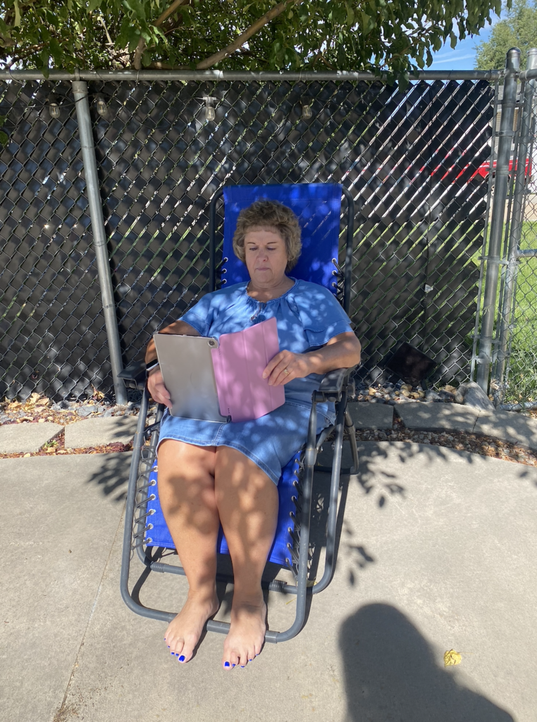 teacher sitting in a lawn chair reading a book