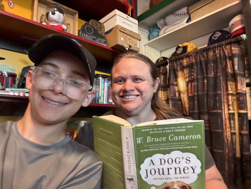 two people smiling as they read a book together
