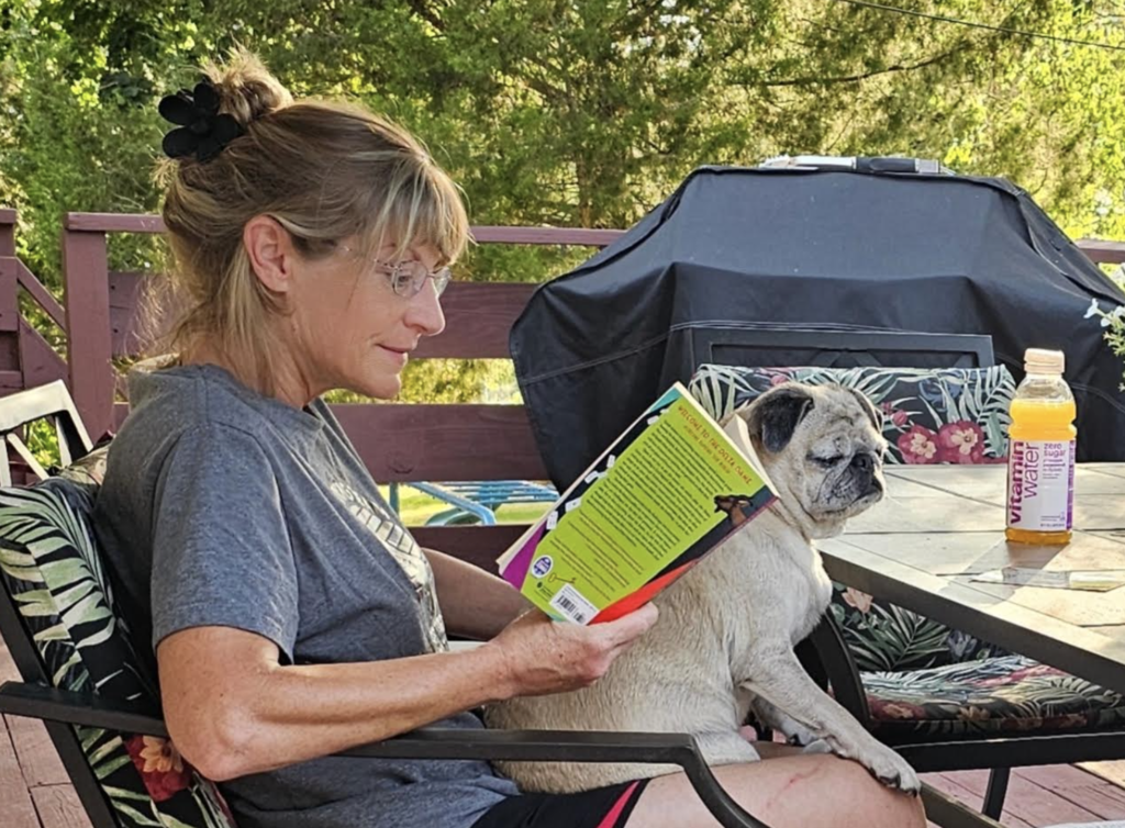woman with a dog sitting on her lap reading a book