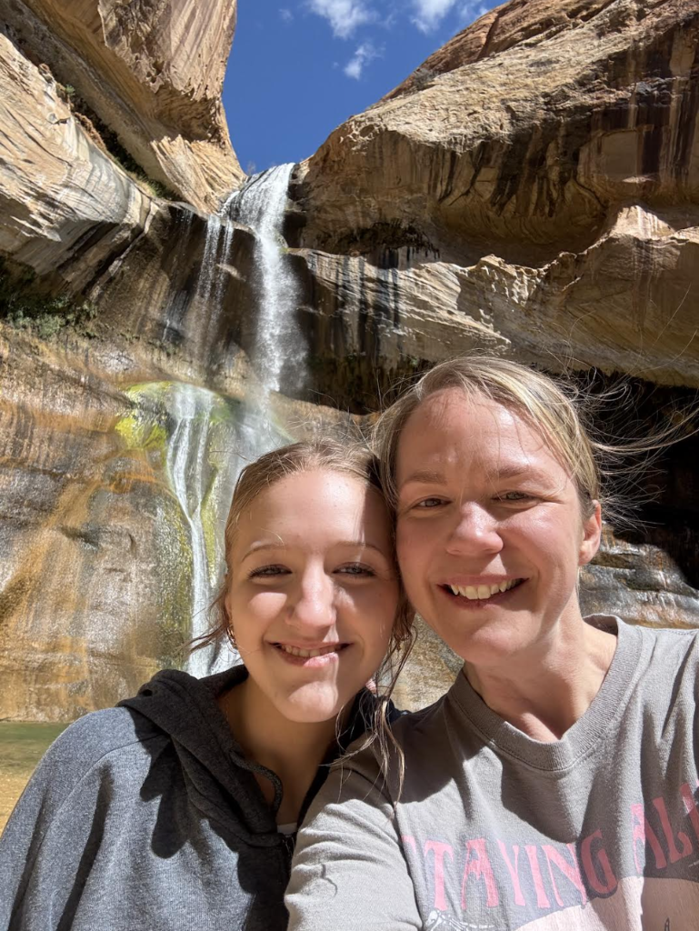 mother and daughter standing in front of a waterfall