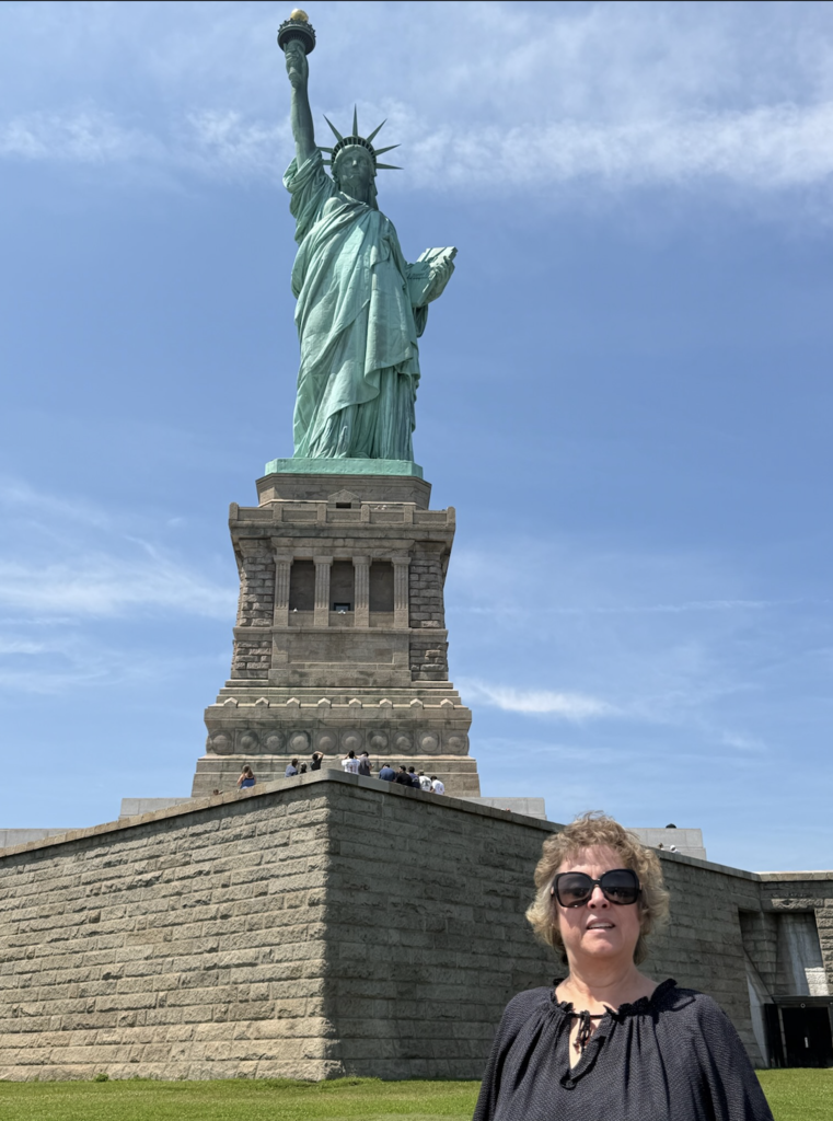 woman standing in front of the statue of liberty