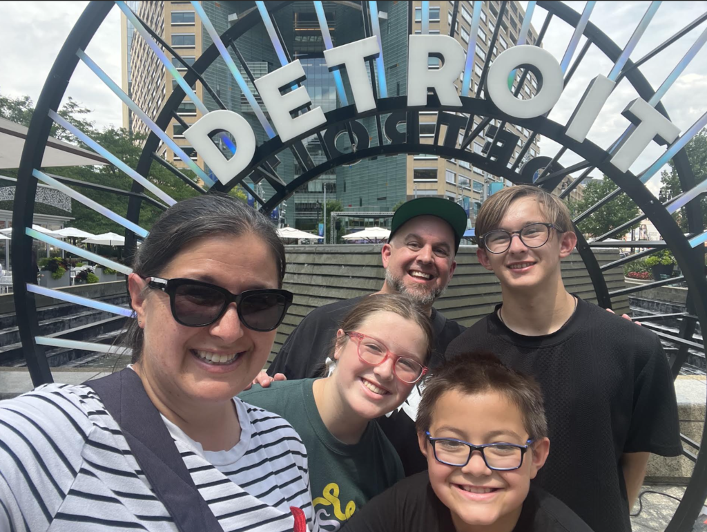 family in front of the detroit sign