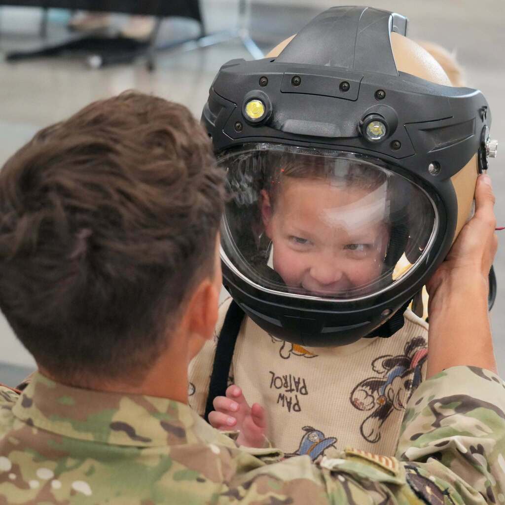 A child trying o a military helmet.