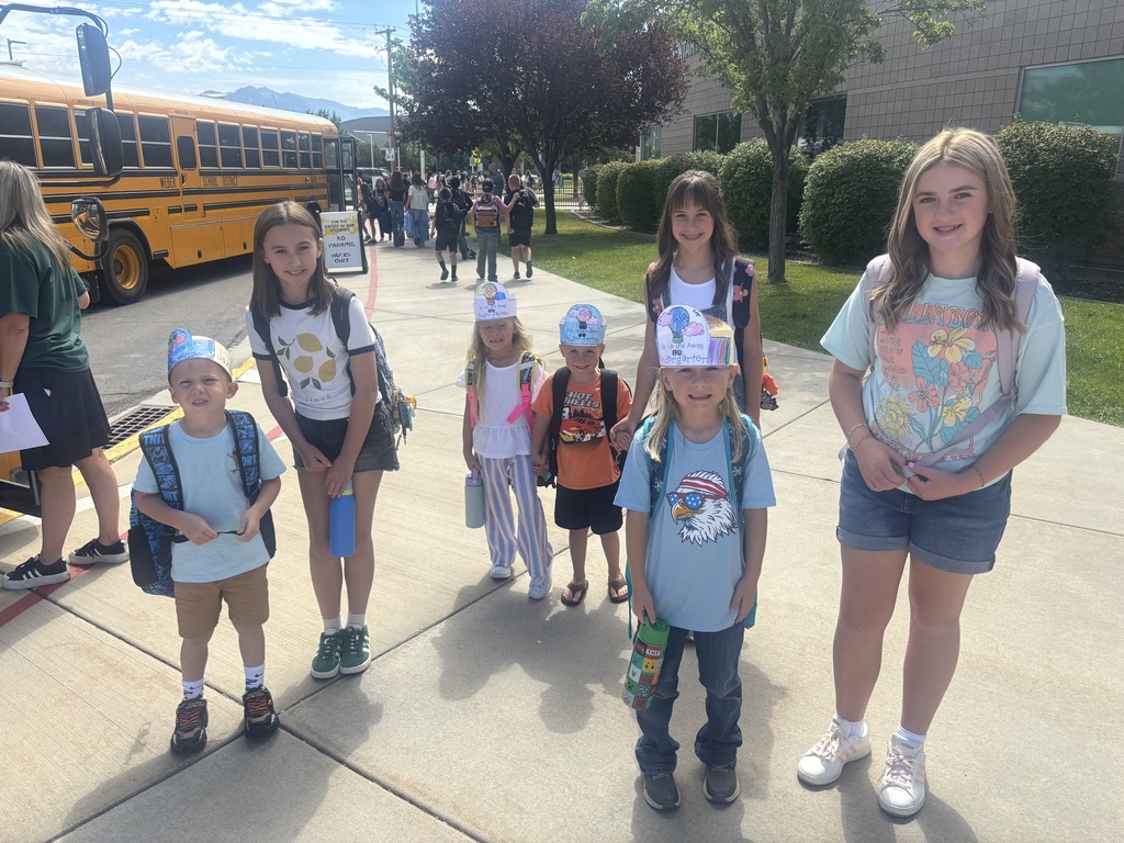 6th grade students outside helping kindergartners catch the bus
