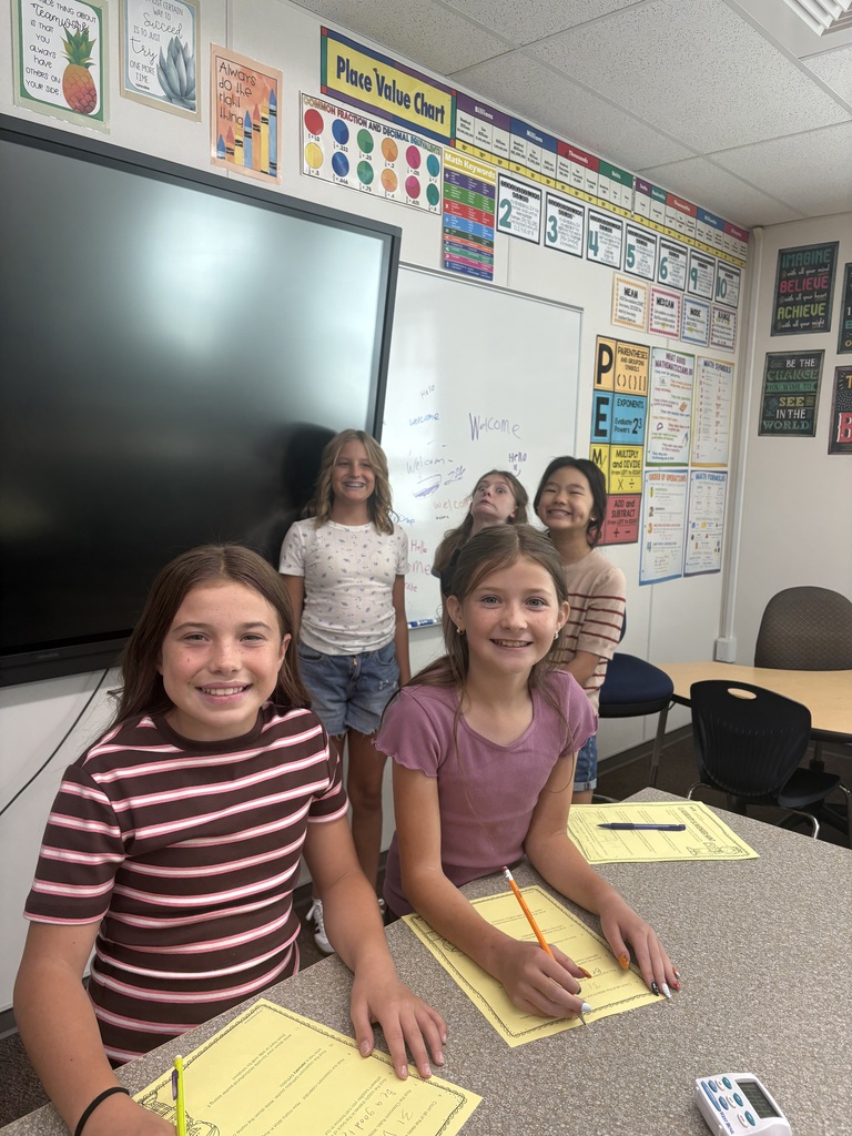 students in class completing a yellow paper worksheet smiling