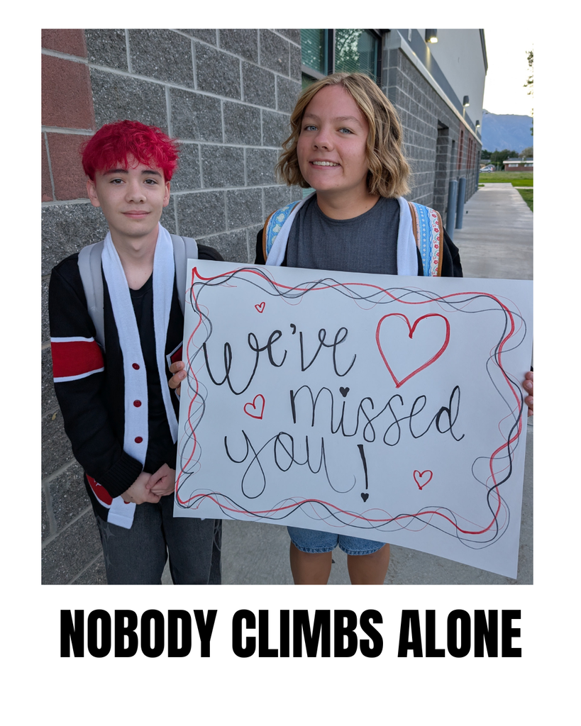 photograph of roy jr leadership welcoming students back with a poster that says we've missed you, 'nobody climbs alone'