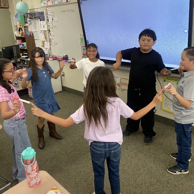 kids in a circle touching markers