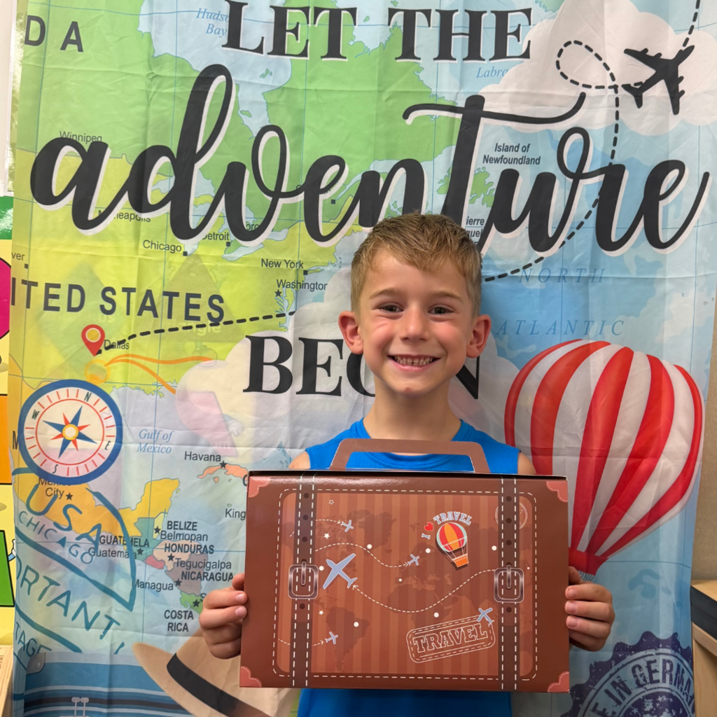 Student standing in front of a banner that says Let the Adventure Begin.